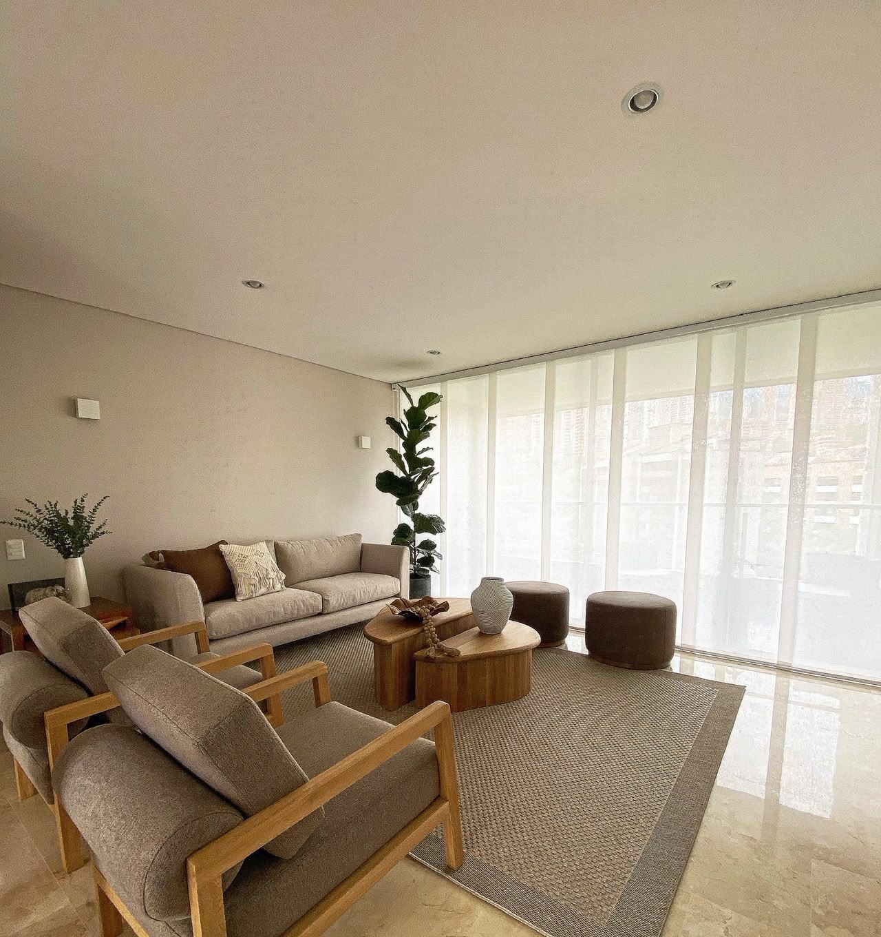 Sala amplia con plantas, sofá beige y cortina velada