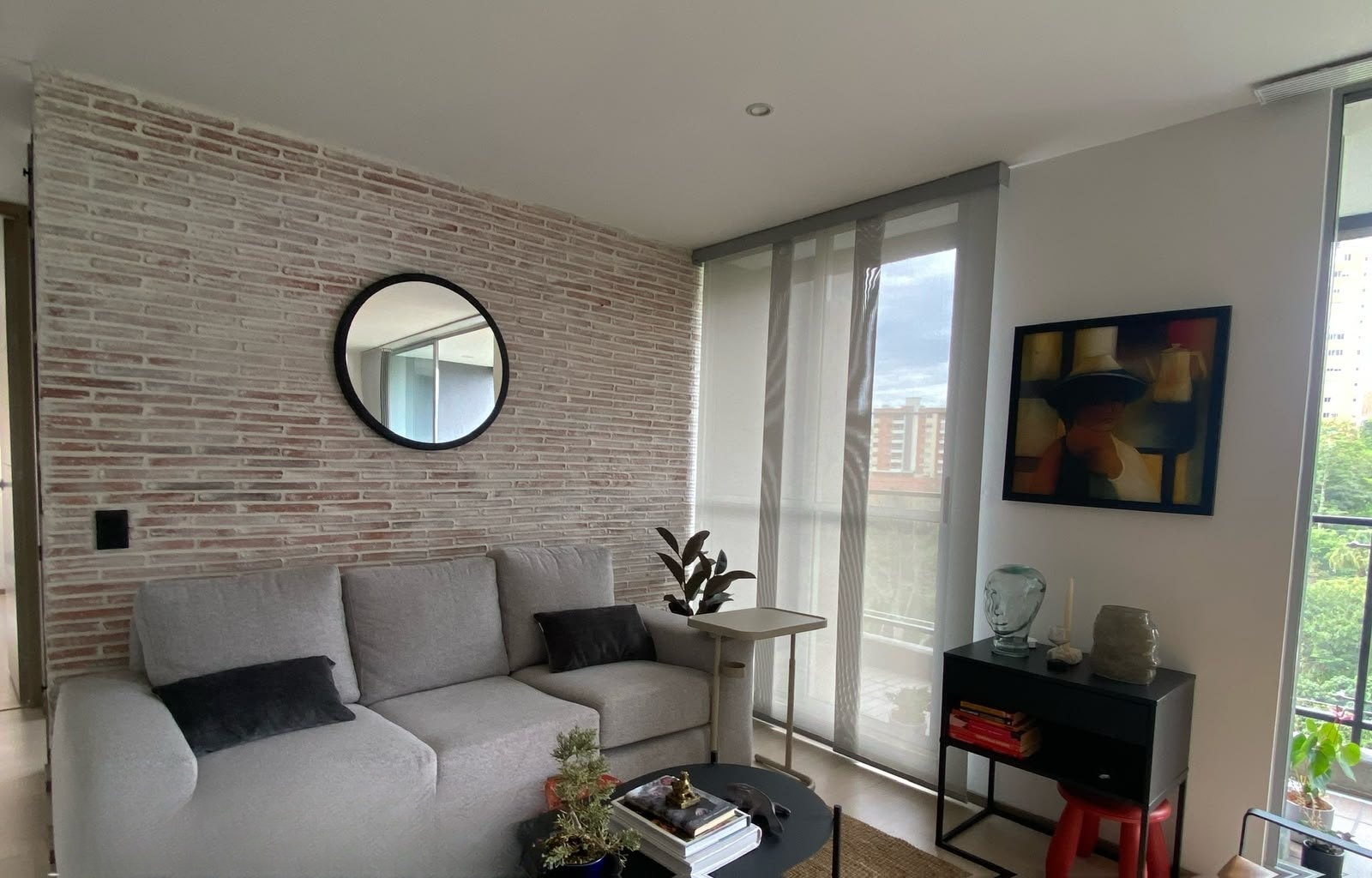 Sala con pared de ladrillo y espejo, cortina instalada